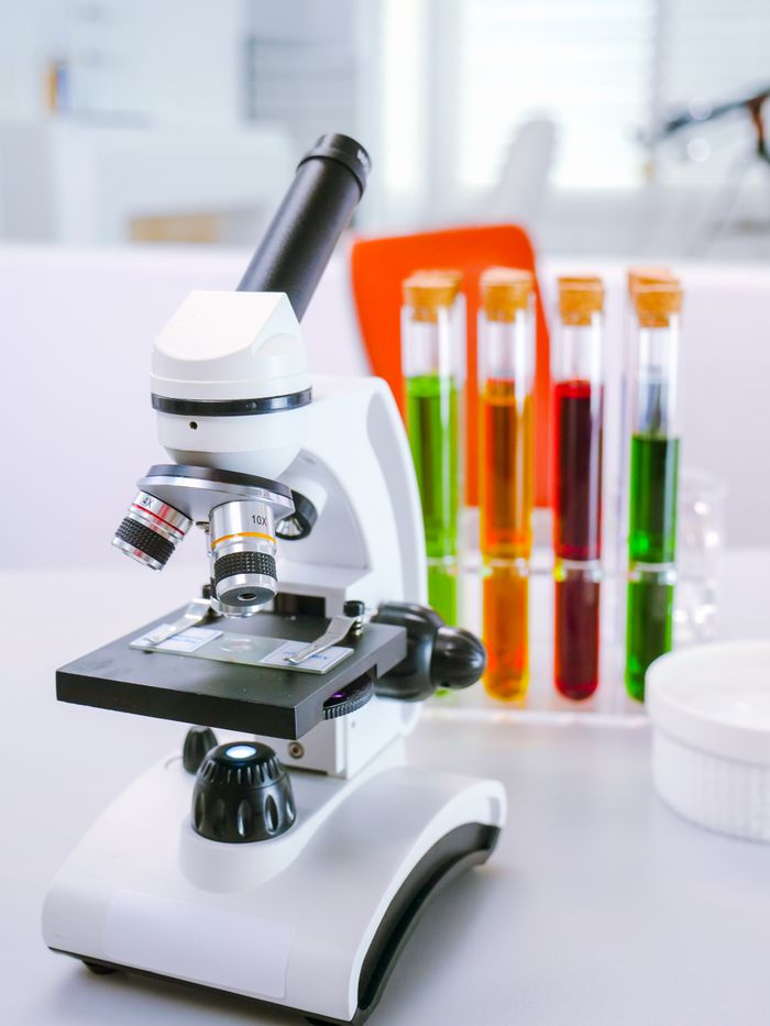 A microscope situated in a laboratory with colorful test tubes, reflecting a scientific environment.